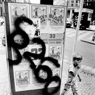 Child walking past vandalized public notice board.