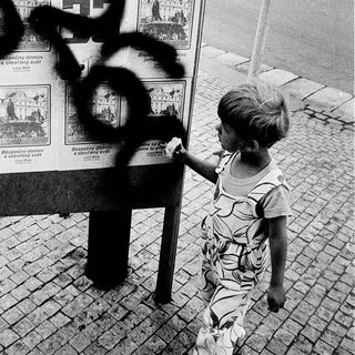 Child touches vandalized billboard with graffiti.