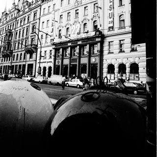 Historic European city street with grand early 20th-century buildings.