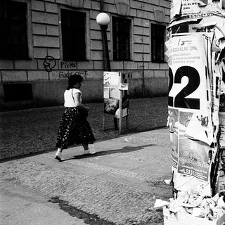 Covered post box with numerous ads, street scene.