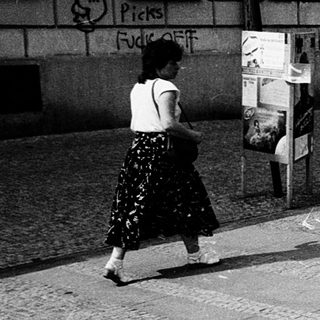 Covered post box with numerous ads, street scene.