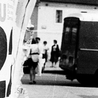 Posters covering a lamppost in urban setting.