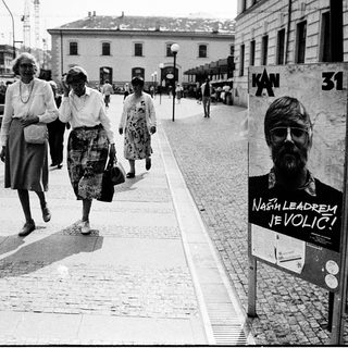 Women walking past political campaign poster.