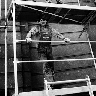 Construction workers on scaffolding performing building maintenance.