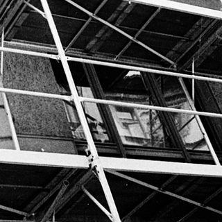 Construction workers on scaffolding performing building maintenance.