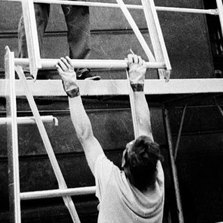 Construction workers on scaffolding performing building repairs.
