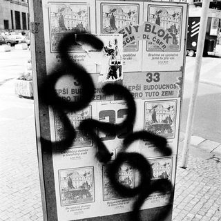 Vandalized poster board with graffiti and defaced text.