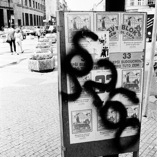Vandalized bulletin board with graffiti in urban setting.