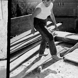 Two men performing skateboard tricks on wooden rails.
