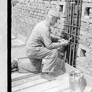 Construction workers building with rebar and brick.