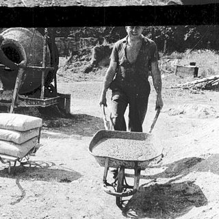 Construction workers mixing concrete manually.