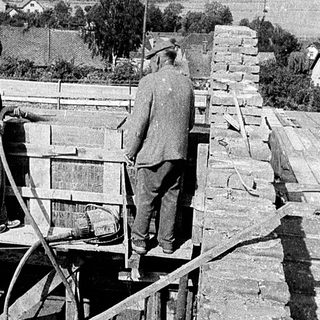 Historic construction workers laying stone on a roof.