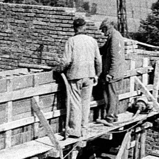 Construction workers installing wooden roofing on a building.