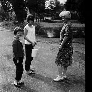 Two adults and two children walking outdoors in residential area.