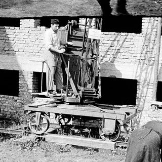 Historical construction site with workers assembling machinery.