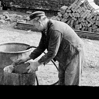 Workers constructing brick wall with manual labor.