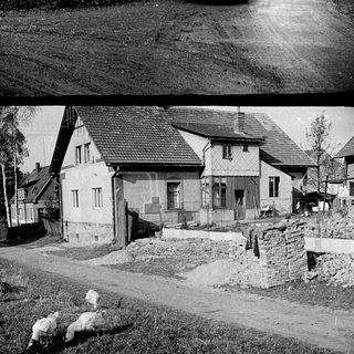 Rural village scene with old van and sheep.