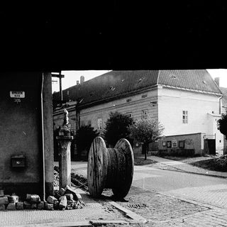 Large wooden wheel on pavement beside old buildings.