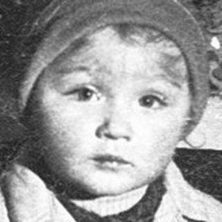 Young child in winter coat, looking solemn.