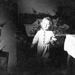 Child in vintage clothing holding a toy.