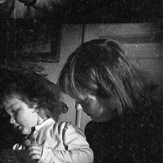 Children playing with flashlight in dimly lit room.