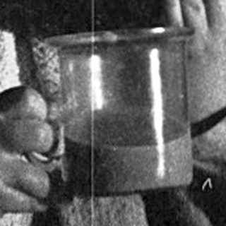 Two children drinking from cups indoors.