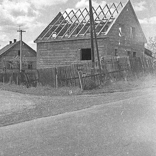 Vintage rural road with old buildings and vehicles.