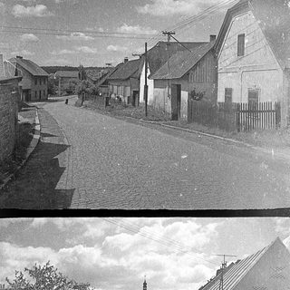 Village street with old houses and church in background.
