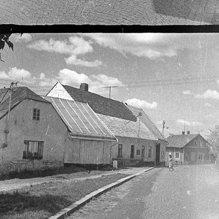 Vintage black-and-white street with rural houses.