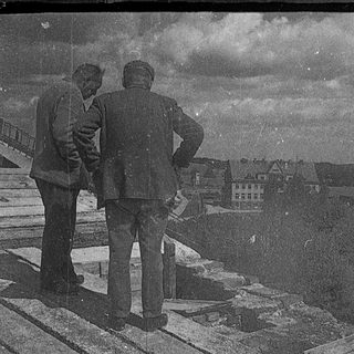 Two men observing cityscape from elevated viewpoint.
