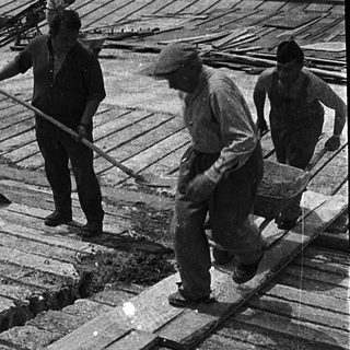 Construction workers installing wooden planking on a rooftop.