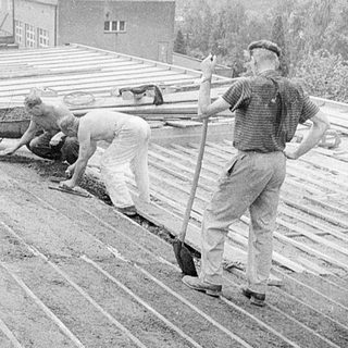 Construction workers laying wooden planks on roof.