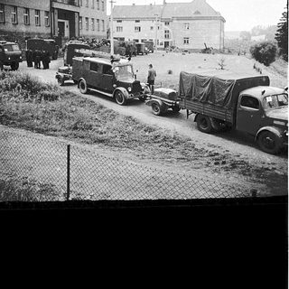 Military trucks and vehicles in rural area during mid-20th century.