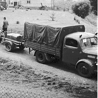 Military trucks and vehicles in rural area during mid-20th century.