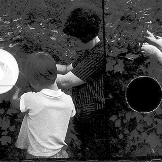 Two people and a child painting or drawing outdoors.