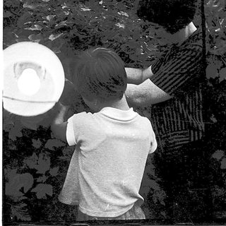 Two people and a child painting or drawing outdoors.