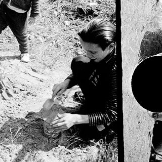 Child playing outdoors while adult kneels nearby.