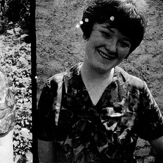 Two women smiling in vintage camouflage-pattern blouses.