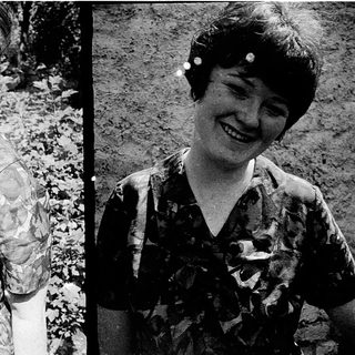 Two women smiling in vintage camouflage-pattern blouses.