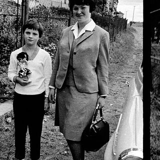 Two women in 1960s-70s attire posing outdoors.