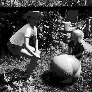 Two children playing with large beach balls outdoors.