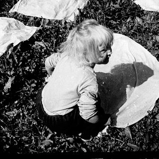 Child playing with spread laundry outdoors.