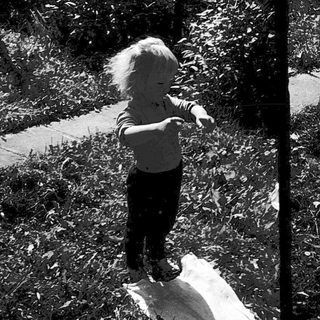Child flying a kite outdoors on grass.