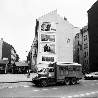 Urban street scene with large billboard, truck, and vintage cars.