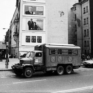 Urban street scene with large billboard, truck, and vintage cars.