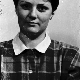 Black-and-white portrait of a woman in plaid shirt.