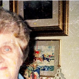 Elderly woman indoors, wearing blue shirt.
