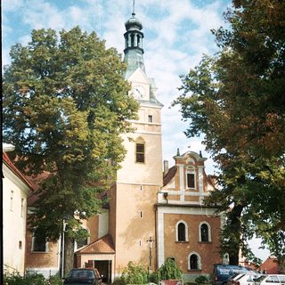 Historic church tower with clock and surrounding buildings.
