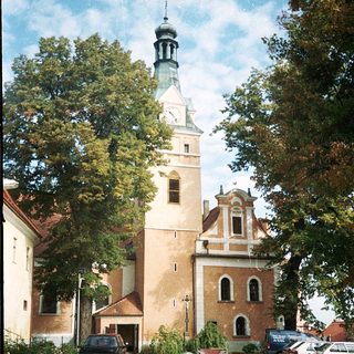 Historic church tower with clock and surrounding buildings.