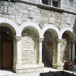 Historic stone courtyard with arched colonnade and fountain.